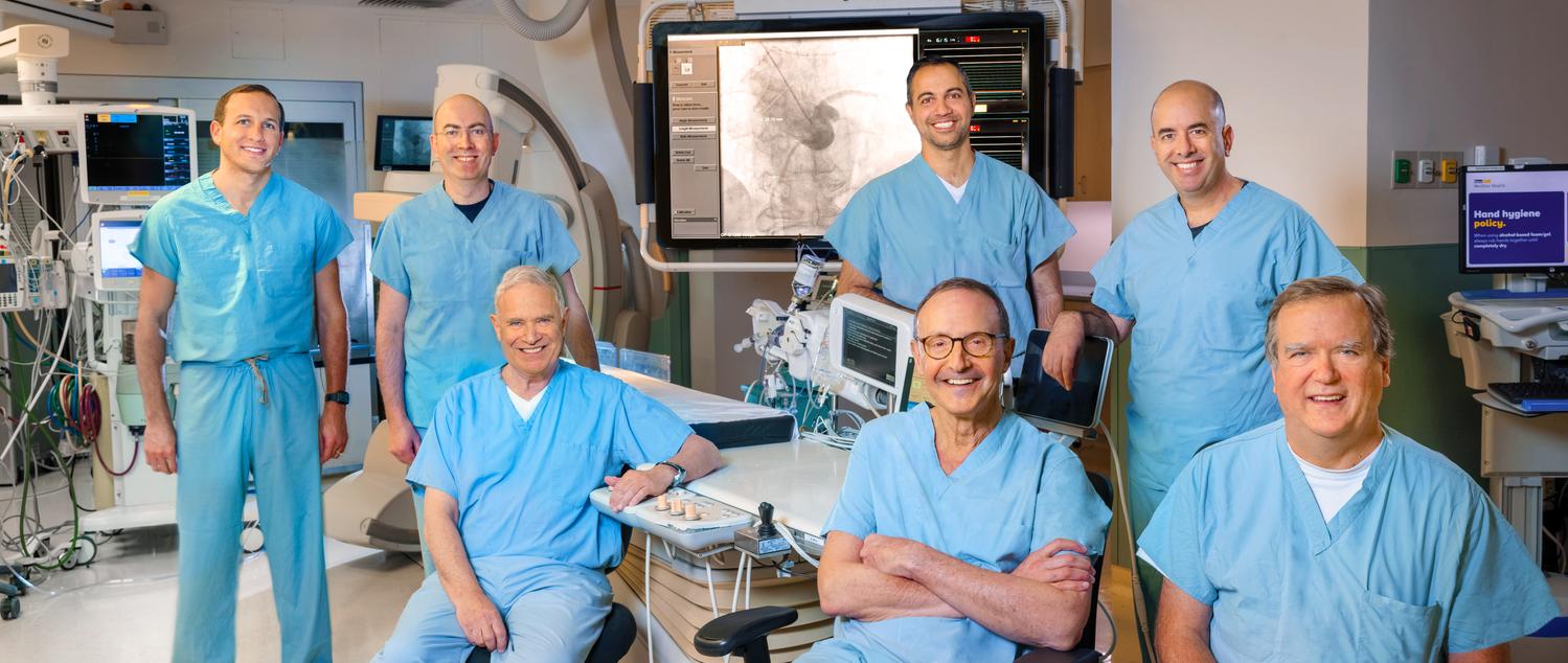 一组MedStar心脏病学医生站在一个被现代技术设备包围的心导管实验室里。
