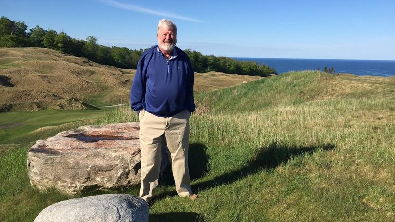 John Freshmans, a gastroenterology patient, stands in a rural field and smiles for the camera.