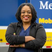 A healthcare professional poses for a photo in front of the MedStar Health mobile healthcare center truck.