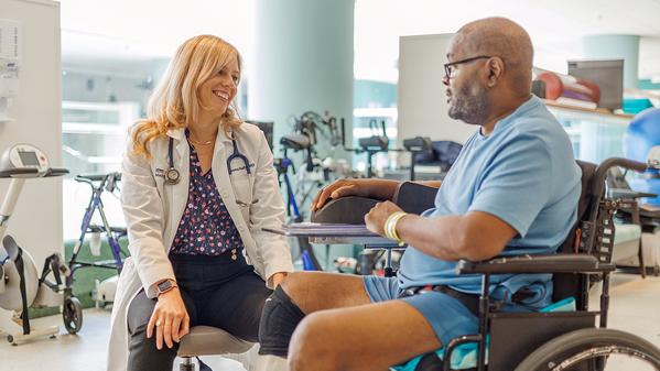 Dr Emma Nally talks with a patient at MedStar National Rehabilitation Center's gym.