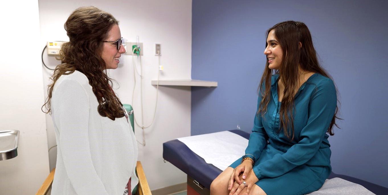 Dr Tara Santum consults with a female patient in a clinical setting.