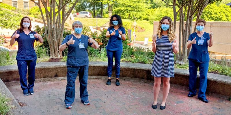5 MedStar Georgetown associates wearing masks, giving a "thumbs up" while standing outside