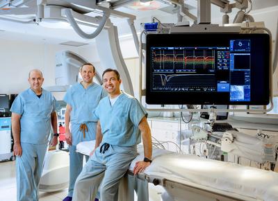 Doctors Itsik Ben-Dor, Brian Case and Hayder Hashim pose for a team photo in the cardiac catheterization lab at MedStar Washington Hospital Center.