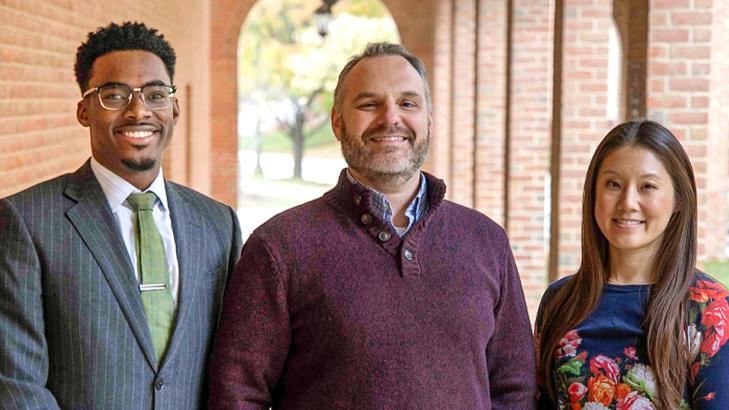 Marck-Arthur Clerveau, Innovation Manager; Steve Kinsey, Director; and Dae Capobianco, Innovation Manager. stand for a group photo in a brick covered walkway with an arched entrance in the background.