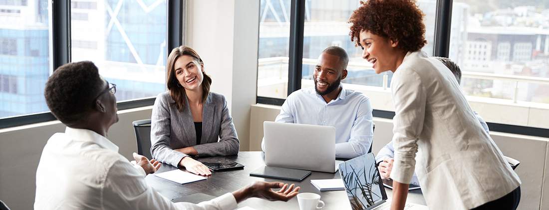 A group of professionals holds a meeting in a corner conference room office.