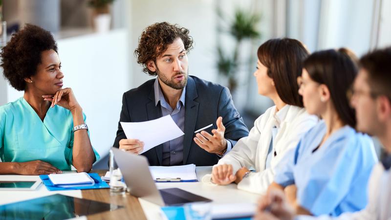 A group of professionals holds a meeting in a corner conference room office.