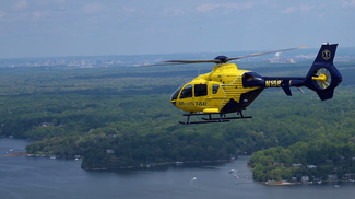 The MedStar helicopter flies over a river shoreline.