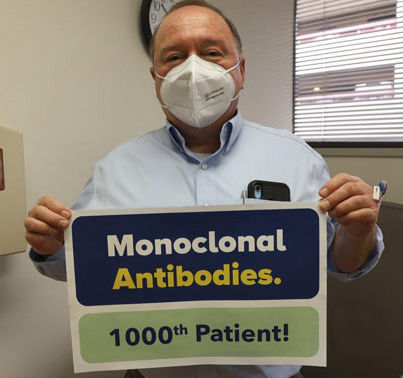 Richard Battista holds a sign indicating that he is the 1000th person that MedStar Health has treated for COVID-19 with monoclonal antibodies.