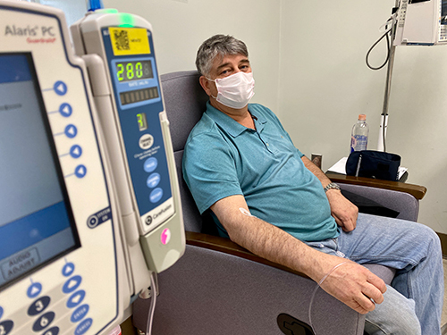 A male patient wearing a mask sits in a chair in a treatment room and receives a monoclonal antibody infusion at MedStar Harbor Hospital