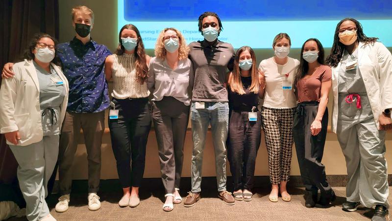 A group of nursing students stand together for a photo indoors. All of the people are wearing masks.