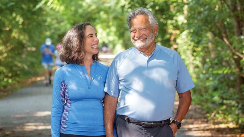 Mark Nash walks on a shaded path with his wife, Donna, who has been by his side throughout his cancer treatment.