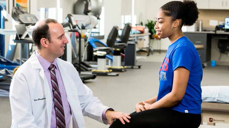Dr. Daniel Hampton talks with a patient in a rehabilitation gym.