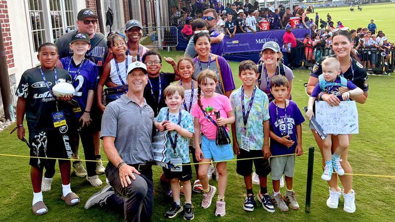Ravens coach John Harbaugh poses for a photo with a group of pediatric cancer patients from MedStar Health - their special guests at training camp.