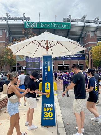 Event patrons apply sunscreen provided by MedStar Health outside of M&T Bank Stadium in Baltimore.