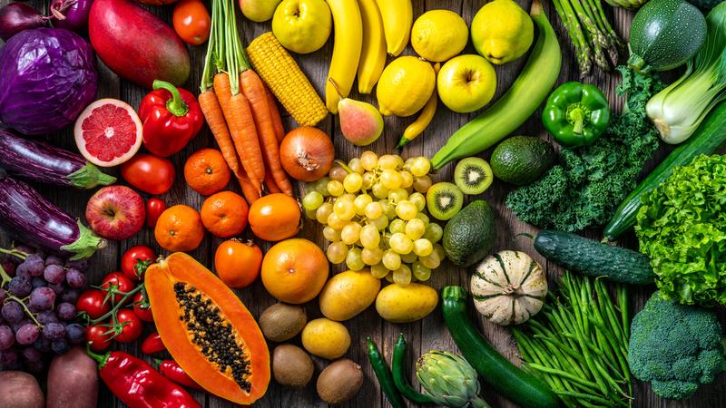 A rainbow of fresh fruits and vegetables is displayed on a table.