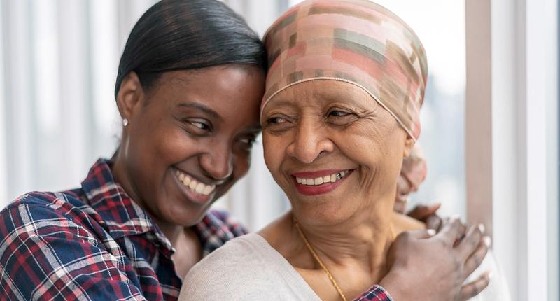 A young woman hugs her older family member who is going through treatment for cancer.