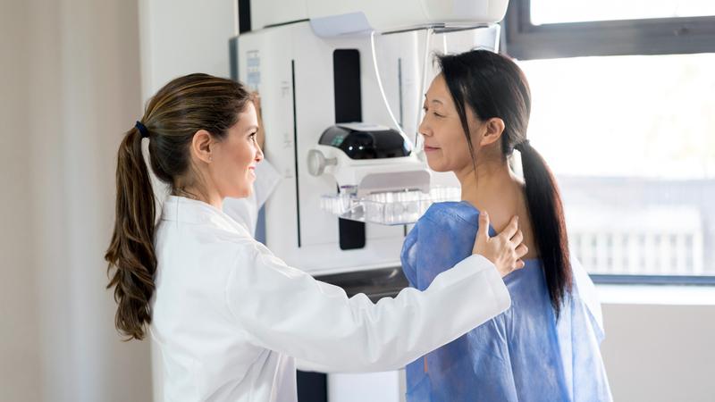 A doctor positions a patient during a routine mammogram screening.