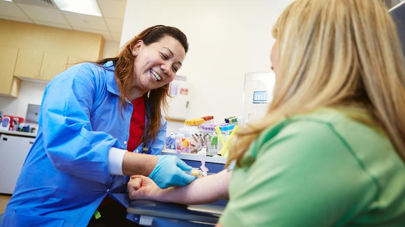 A nurse draws blood from a patient in a hospital.