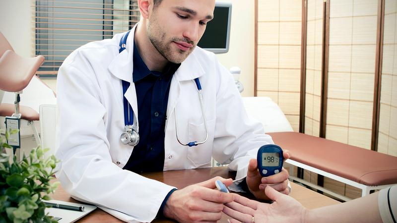 A doctor tests a patient's blood glucose level during an office visit.