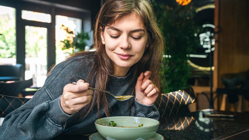 A woman enjoys a bowl of food in a restaraunt.