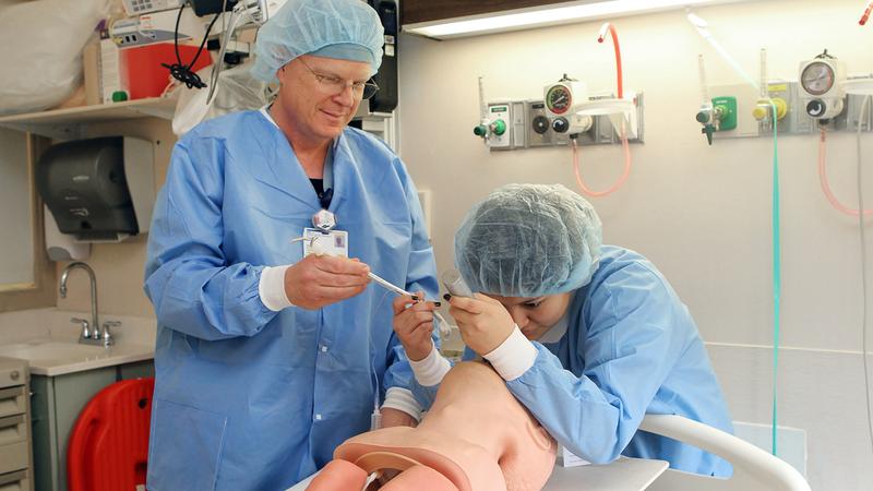 Dr Clyde Pray oversees a medical student practicing intubation technique on a simulation mannequin.