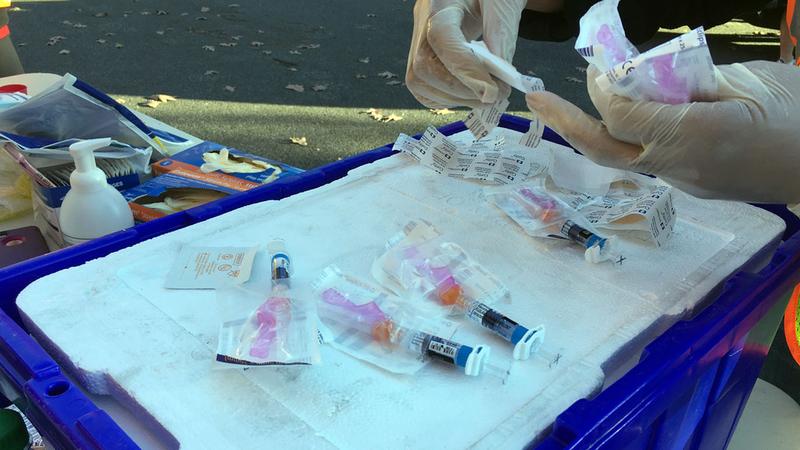 close up photo of gloved hands and flu vaccine syringes