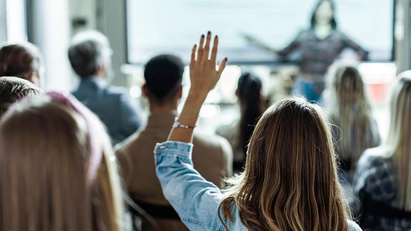 A woman raises her hand during a classroom training activity.