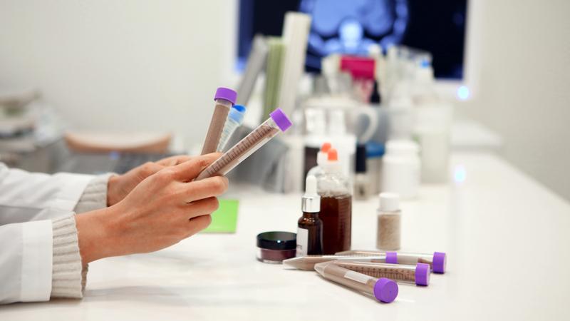 Close up of hands holding test tubes in a laboratory setting.