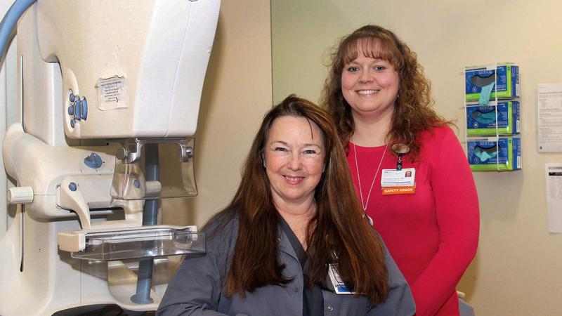 Nurse Navigators Christine Taylor and Cheryl Pauley pose for a photo near a mammography scanning machine.