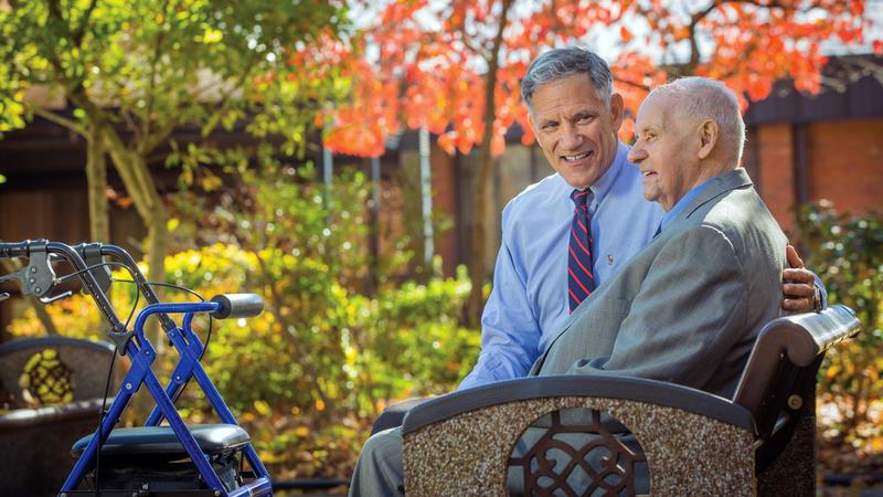 Dr Arthur Flatau sits with a patient outdoors.