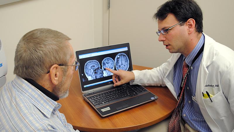 Dr Peter Turkeltaub shows brain imaging scans to a patient.