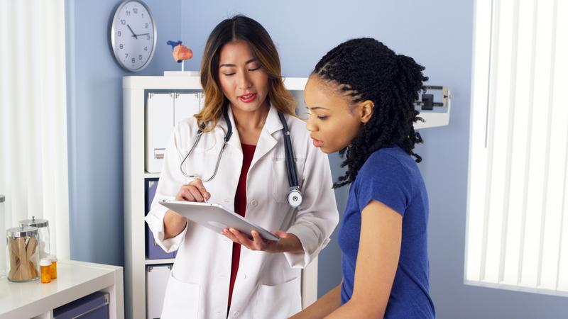 A female doctor talks with a female patient in a medical office.