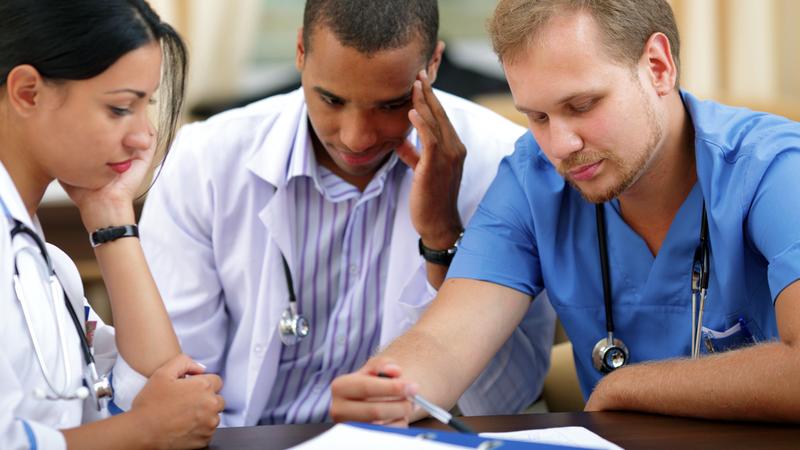 Three doctors sit together and study a case.