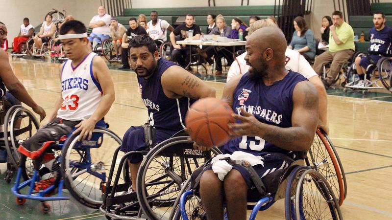 A group of men plays wheelchair basketball in a gymnasium.