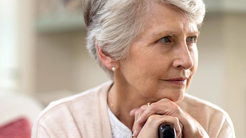 A mature woman sits with her chin on her hands as she is thinking.