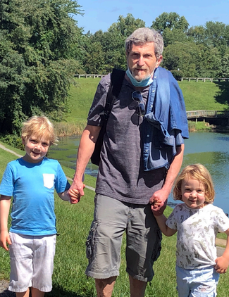 Ed Gershkovich holds hands with his 2 young grandsons in a park outdoors.