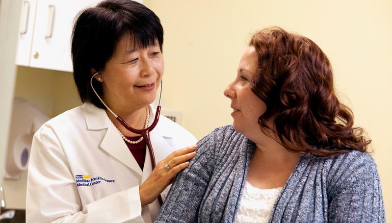 Dr. Atsuko Okabe examines a patient in a medical office.