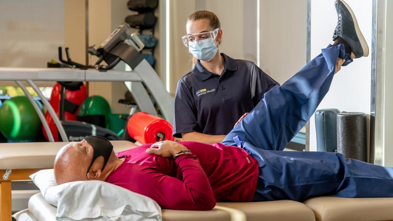 A physical therapist holds the leg of a patient during a therapy session.