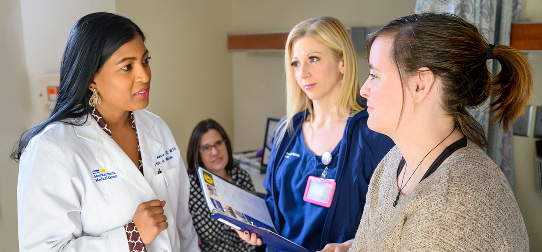 Dr Anita Tammara and a nurse talk with a patient.