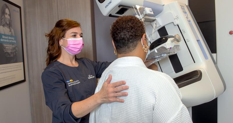 MedStar Health mammography technician Laura Stottlemyer consults with a patient in front of a mammography machine.