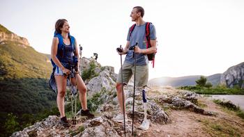 A young couple hikes outdoors. The man has a prosthetic leg.
