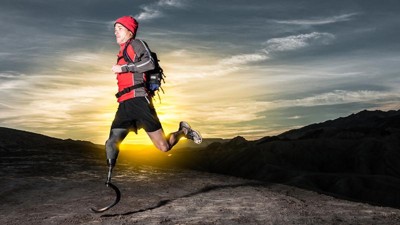 A man with a prosthetic leg runs at sunrise.