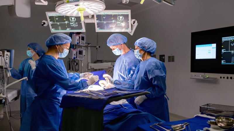 A team of surgeons works in an operating room.