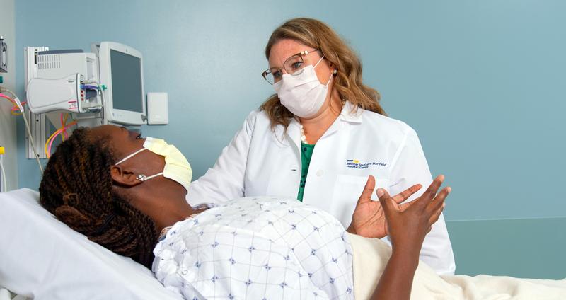 A doctor talks with a female patient in a clinical setting.