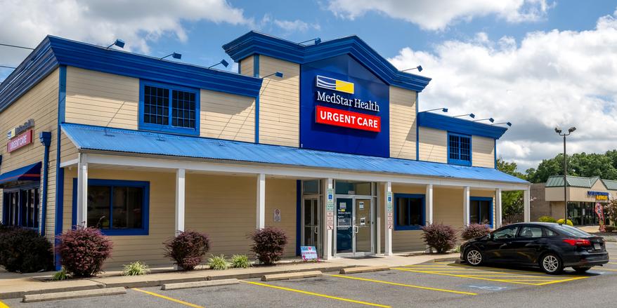 Front entrance to a blue and yellow building - MedStar urgent care at Waldorf Shoppers World
