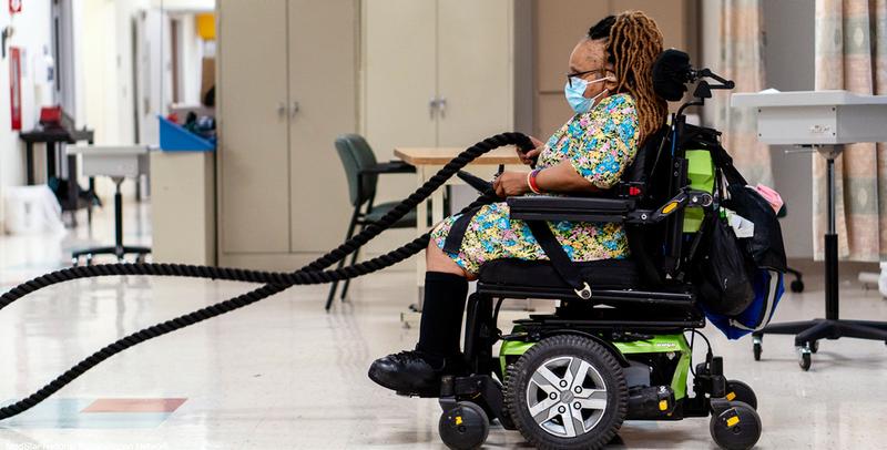 A young woman in a wheelchair works with weighted ropes in MedStar Health's adaptive fitness gym.