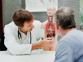 医生在门诊期间使用解剖模型与病人谈论肾上腺疾病。