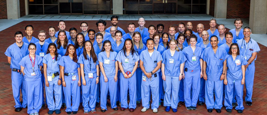 Team photo taken outdoors of the Anesthesiology Department at MedStar Georgetown University Hospital. All of the doctors are wearing blue scrubs.