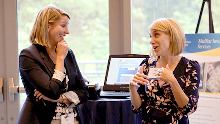 Two women talk at a MedStar Health research symposium event.