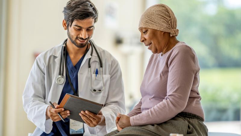 A doctor talks with a cancer patient in a clinical setting.